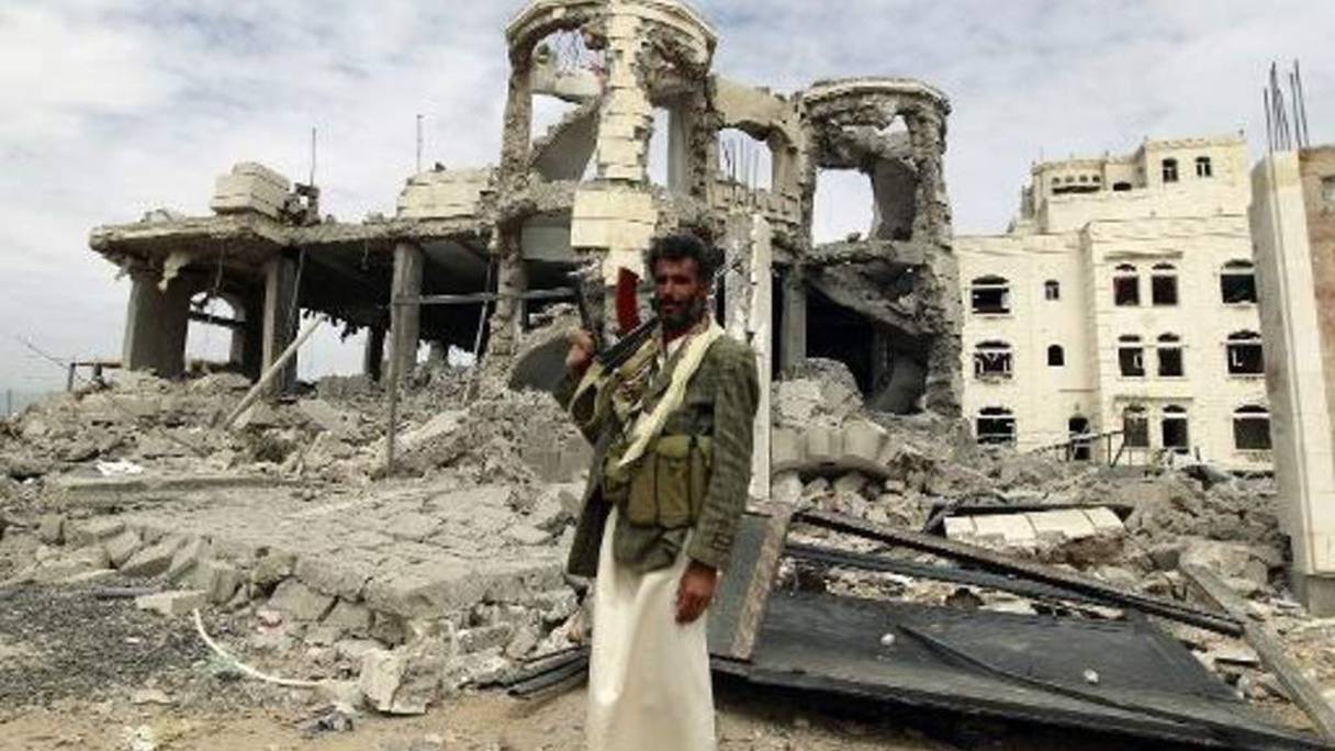 Un milicien Houthi pose devant une maison détruite par un bombardement, le 29 mai.
